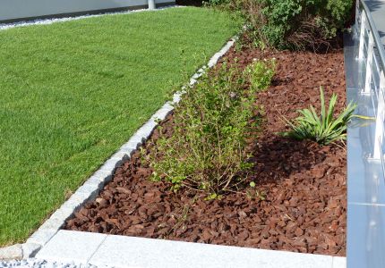 Rollrasen neben beflanztem Rindenmulch-Streifen