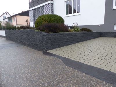 Mauer aus dunkelgrauen Pflastersteinen